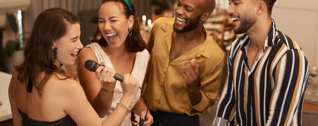 Freunde singen gemeinsam Karaoke und haben dabei sichtlich Spaß – perfekte Stimmung für eine gelungene Hochzeitsüberraschung.