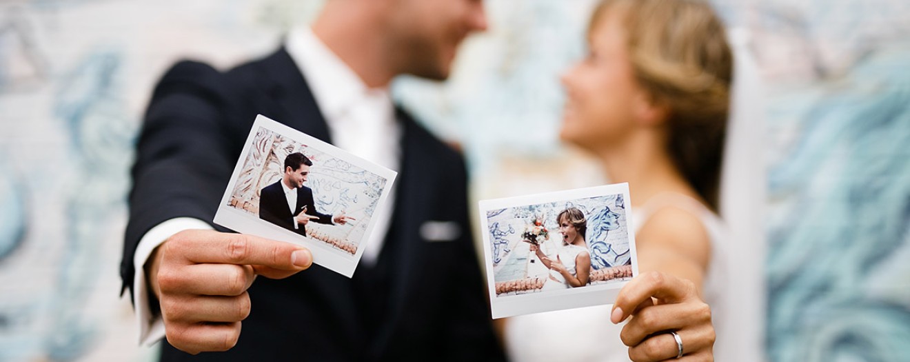 Polaroids von Brautpaar im Fokus während das Paar im Hintergrund verschwommen zu sehen ist