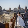 The bride and groom walk on the background of the old castle.