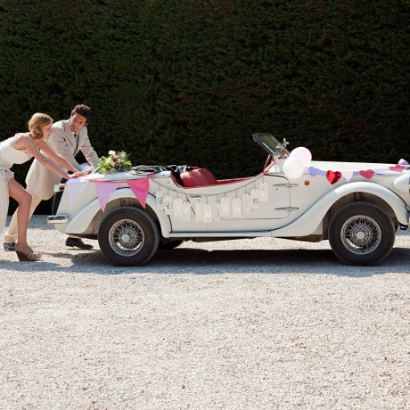 Newlyweds pushing broken down vintage car