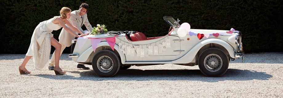 Newlyweds pushing broken down vintage car