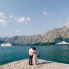 Bride and groom hug on the pier against the backdrop of liners and mountains. Back view