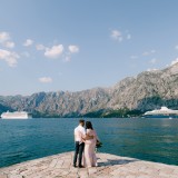 Bride and groom hug on the pier against the backdrop of liners and mountains. Back view