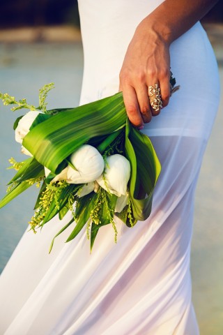 Braut hält einen minimalistischen Brautstrauß aus weißen Tulpen und großen grünen Blättern in der Hand, kombiniert mit einem goldenen Statement-Ring.