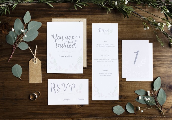 Hochzeitseinladung, rsvp, Menü und Tischkarte neben Ringen und Blättern dekoriert