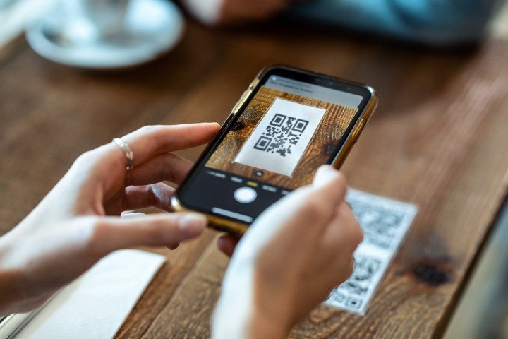 Frau scannt QR Code auf Hochzeitseinladung