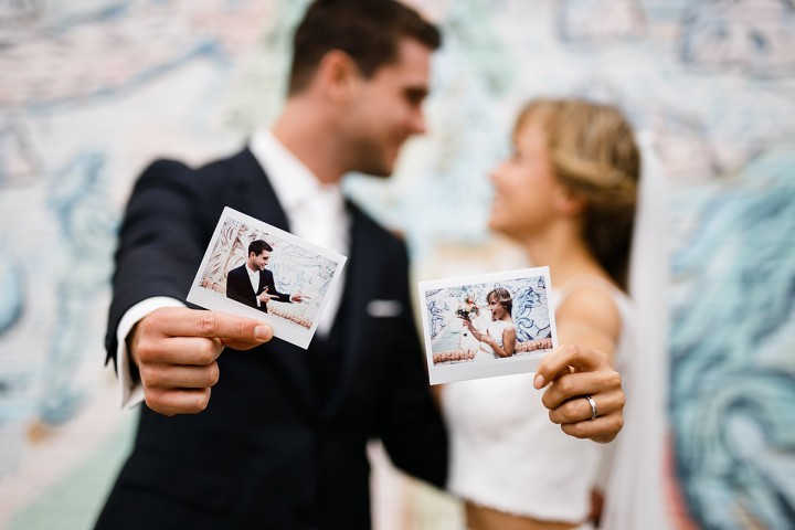Polaroids von Brautpaar im Fokus während das Paar im Hintergrund verschwommen zu sehen ist